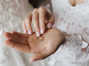 Kobieta ubrana w suknię ślubną, trzymająca w ręce pierścionek zaręczynowy