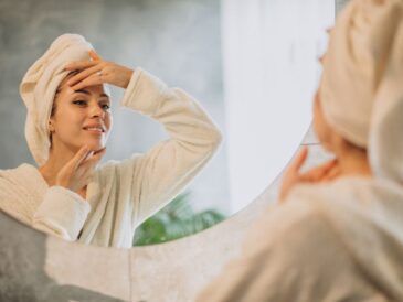 Kobieta oglądająca się w lustrze, ubrana w szlafrok i z ręcznikiem na głowie