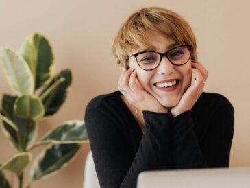 Uśmiechnięta kobieta siedząca przy biurku przed komputerem