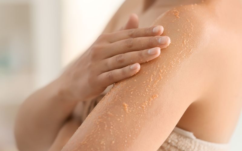 Osoba nakładająca peeling na ramię