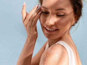 Uśmiechnięta kobieta nakłada peeling na twarz i ramię