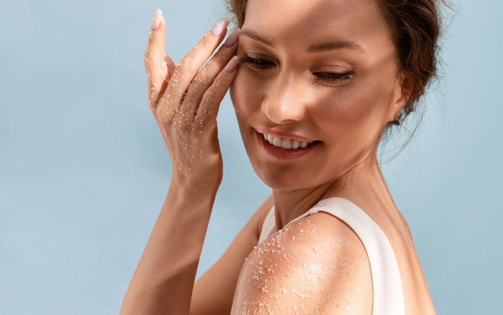 Uśmiechnięta kobieta nakłada peeling na twarz i ramię