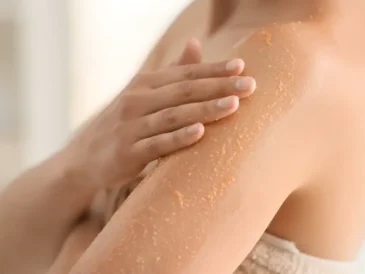 Osoba nakłada peeling na ramię, pokazując złuszczanie skóry