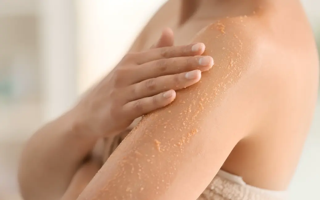 Osoba nakłada peeling na ramię, pokazując złuszczanie skóry