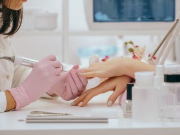 Profesjonalna stylistka paznokci, nosząc różowe rękawiczki w dobrze wyposażonym salonie kosmetycznym