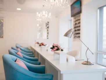 Eleganckie wnętrze salonu kosmetycznego z rzędem niebieskich foteli i białymi stanowiskami do manicure