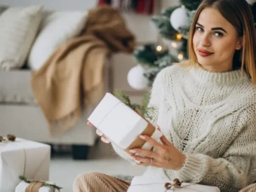 Młoda kobieta trzyma świąteczny prezent w białym papierze z ozdobnym sznurkiem